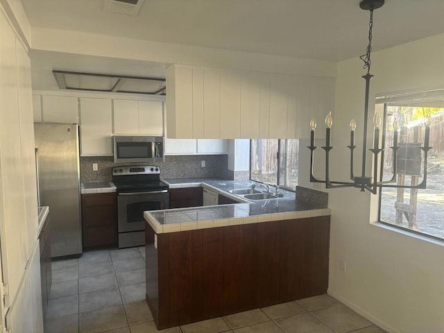 kitchen featuring stainless steel appliances, white cabinetry, light tile patterned floors, and kitchen peninsula