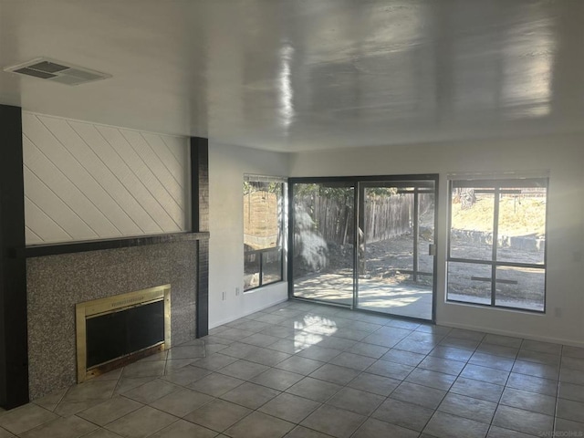 unfurnished living room with a tiled fireplace and tile patterned flooring