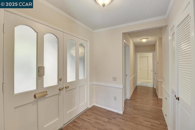 entrance foyer featuring crown molding, a textured ceiling, and light hardwood / wood-style flooring