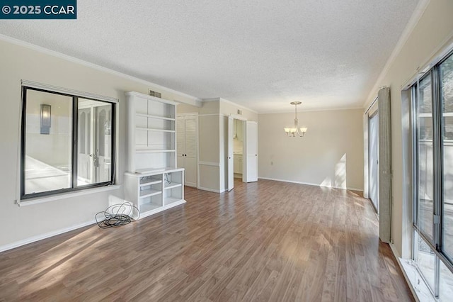 interior space with hardwood / wood-style flooring, a textured ceiling, a chandelier, and a healthy amount of sunlight