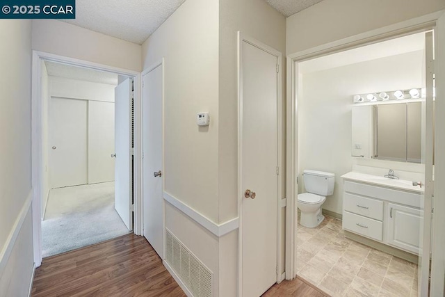 bathroom with vanity, toilet, wood-type flooring, and a textured ceiling