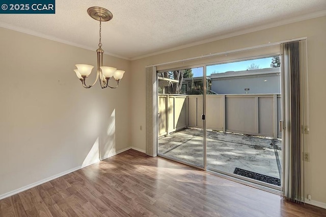 unfurnished room with a textured ceiling, ornamental molding, a chandelier, and hardwood / wood-style flooring