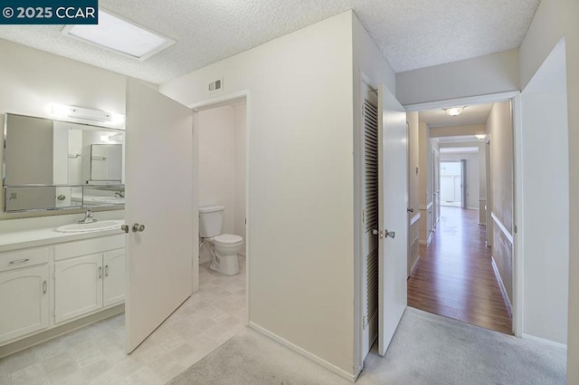 bathroom featuring vanity, a textured ceiling, and toilet