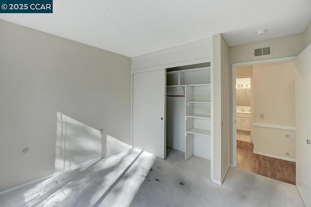 unfurnished bedroom featuring light carpet, a textured ceiling, and a closet