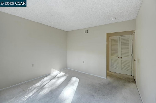 unfurnished room with light colored carpet and a textured ceiling