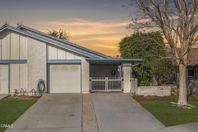 mid-century modern home featuring an attached garage, fence, concrete driveway, stucco siding, and board and batten siding