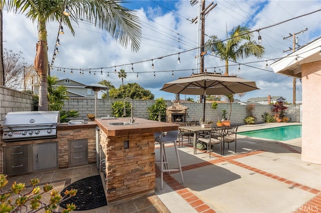 view of patio featuring a fenced in pool, area for grilling, an outdoor fireplace, and an outdoor wet bar