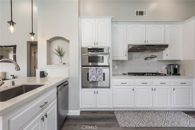 kitchen featuring appliances with stainless steel finishes, tasteful backsplash, sink, white cabinets, and hanging light fixtures