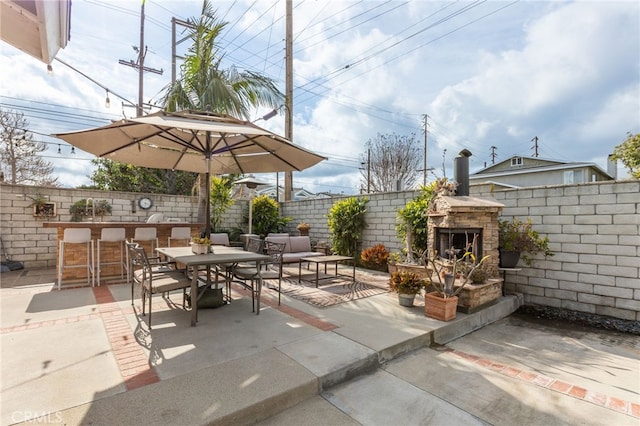 view of patio featuring an outdoor stone fireplace and exterior bar