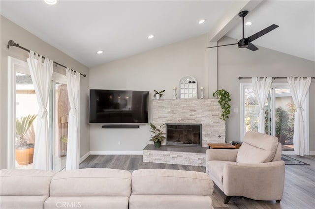 living room with hardwood / wood-style floors, a stone fireplace, lofted ceiling with beams, and ceiling fan