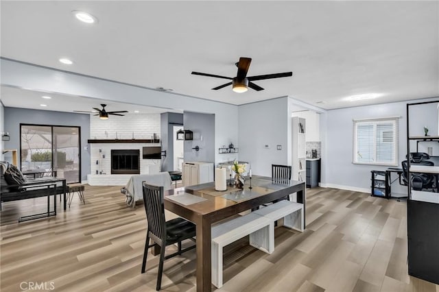 dining room with ceiling fan, hardwood / wood-style floors, and a fireplace