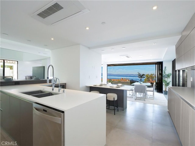 kitchen featuring sink, gray cabinetry, a center island with sink, dishwasher, and a wealth of natural light