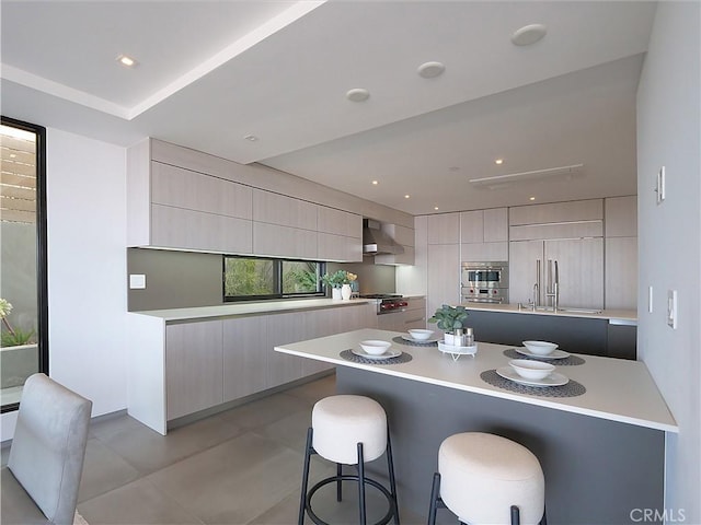 kitchen with a kitchen bar, wall chimney exhaust hood, paneled refrigerator, double oven, and a large island