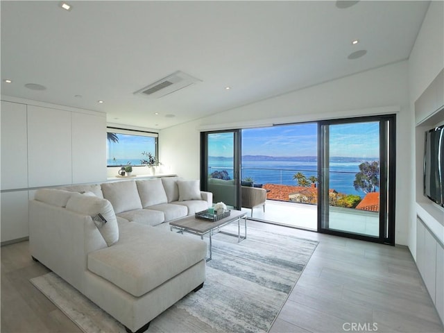 living room with a water view, lofted ceiling, and plenty of natural light