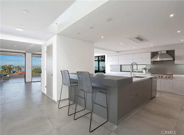 kitchen featuring sink, a wall of windows, a large island, stainless steel gas cooktop, and wall chimney exhaust hood