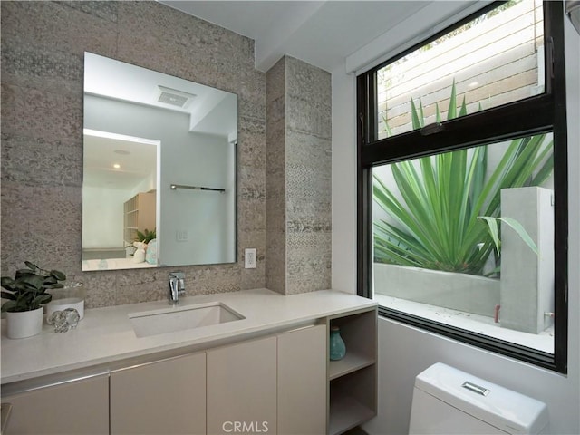 bathroom featuring vanity, toilet, and decorative backsplash