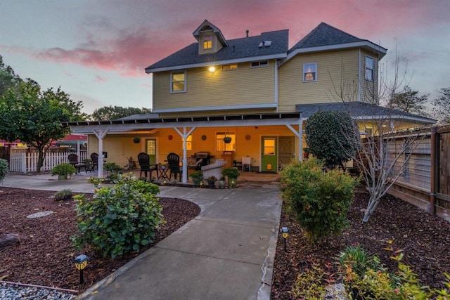 back house at dusk featuring a patio area