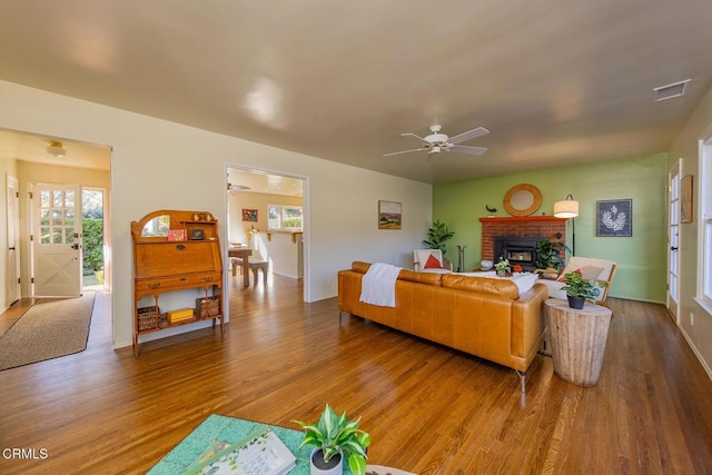 living room with a brick fireplace, hardwood / wood-style floors, and ceiling fan