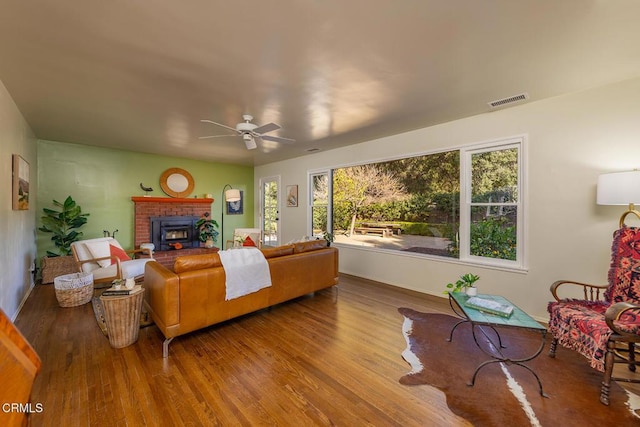 living room featuring ceiling fan, wood-type flooring, and a fireplace