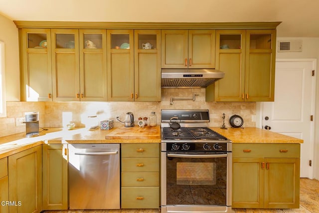 kitchen featuring extractor fan, wood counters, backsplash, stainless steel dishwasher, and gas range