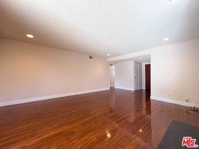 unfurnished room featuring dark hardwood / wood-style flooring and a textured ceiling