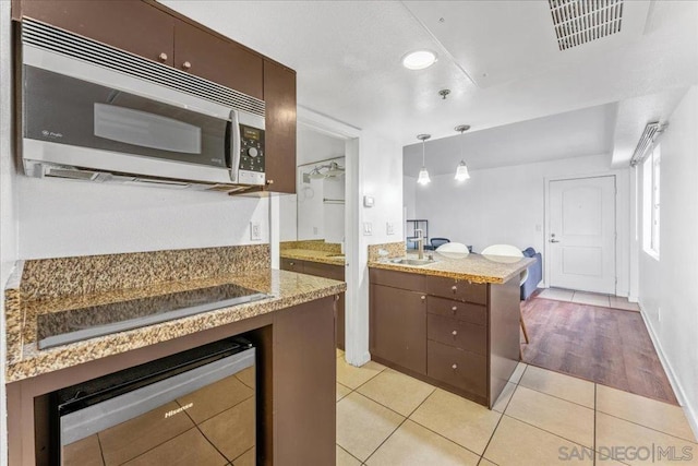 kitchen featuring pendant lighting, sink, dark brown cabinets, light tile patterned flooring, and black electric cooktop