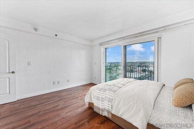 bedroom with dark wood-type flooring, access to outside, and a water view