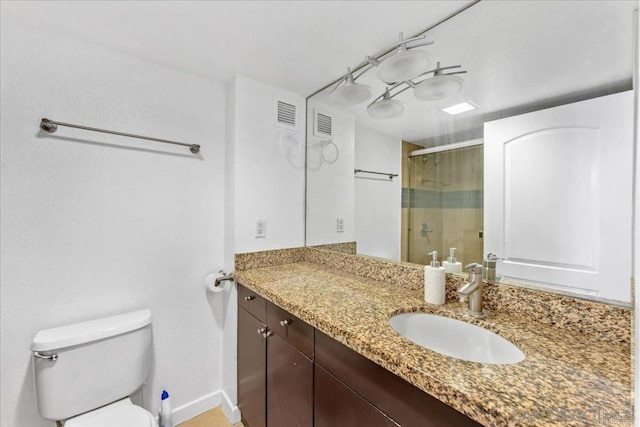 bathroom with vanity, toilet, and a shower with shower door