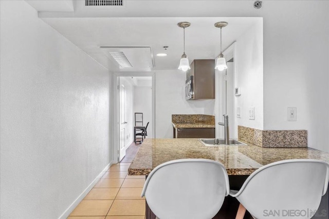 kitchen featuring decorative light fixtures, sink, light tile patterned floors, and kitchen peninsula