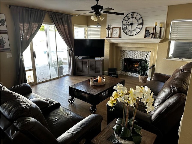 living room featuring hardwood / wood-style flooring, a tile fireplace, and ceiling fan