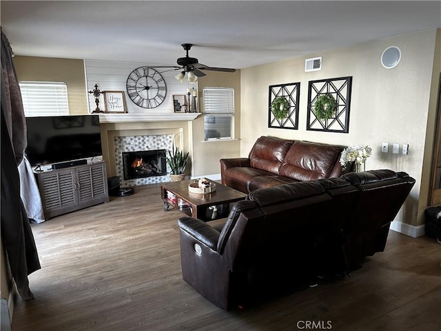 living room with a tiled fireplace, hardwood / wood-style floors, and ceiling fan