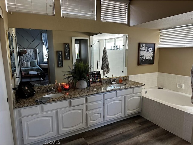 bathroom with vanity, wood-type flooring, and a relaxing tiled tub