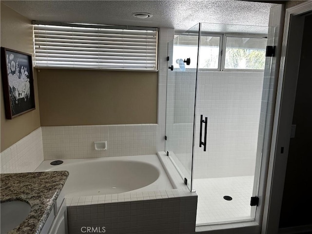 bathroom with vanity, a textured ceiling, and separate shower and tub