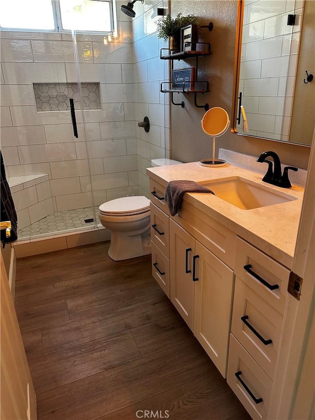 bathroom featuring vanity, hardwood / wood-style flooring, toilet, and walk in shower