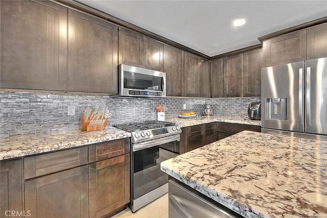 kitchen with light stone countertops, appliances with stainless steel finishes, dark brown cabinetry, and decorative backsplash