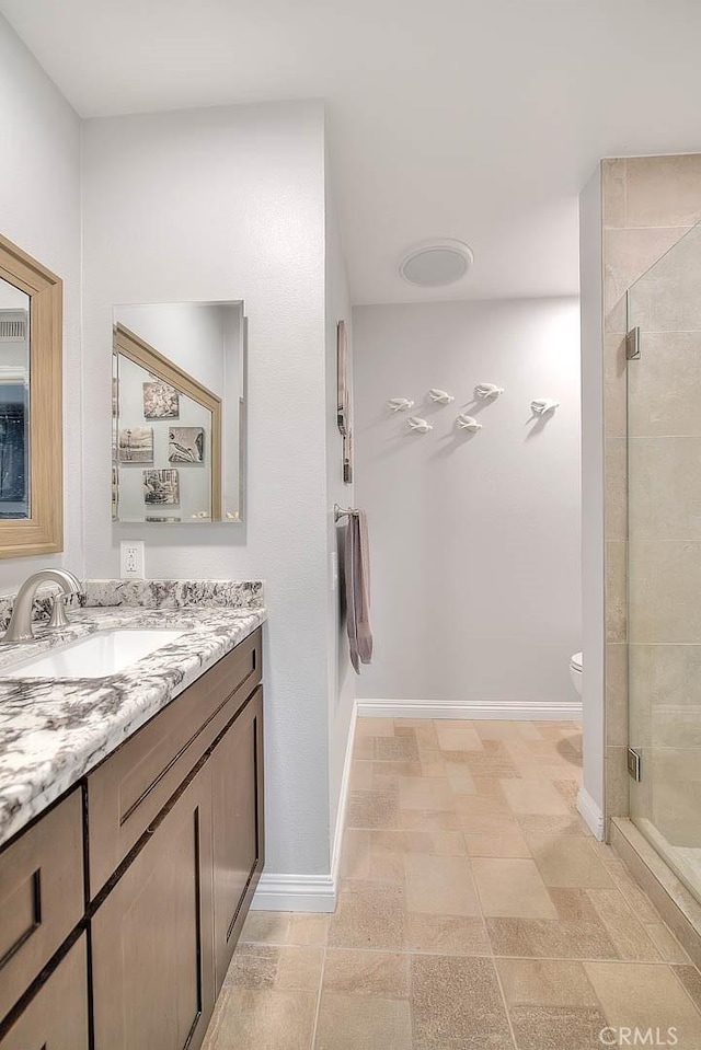 bathroom with a shower with door, vanity, and toilet