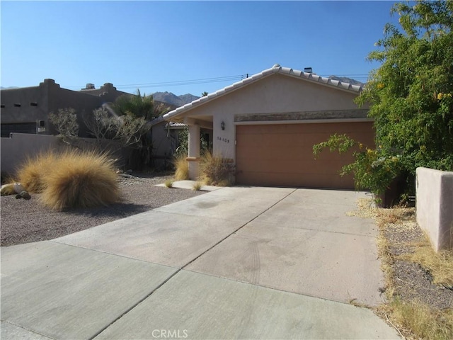 view of front of house featuring stucco siding, a tiled roof, concrete driveway, and a garage