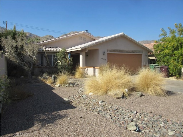 view of front facade featuring a garage, a tile roof, driveway, and stucco siding