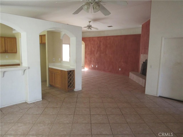 unfurnished living room with visible vents, a tile fireplace, and ceiling fan