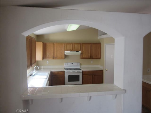 kitchen with white range with electric cooktop, under cabinet range hood, a sink, tile countertops, and a peninsula