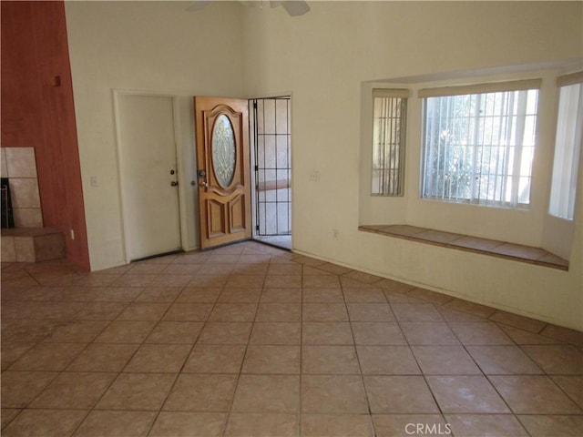 entrance foyer featuring light tile patterned floors, a towering ceiling, and a ceiling fan