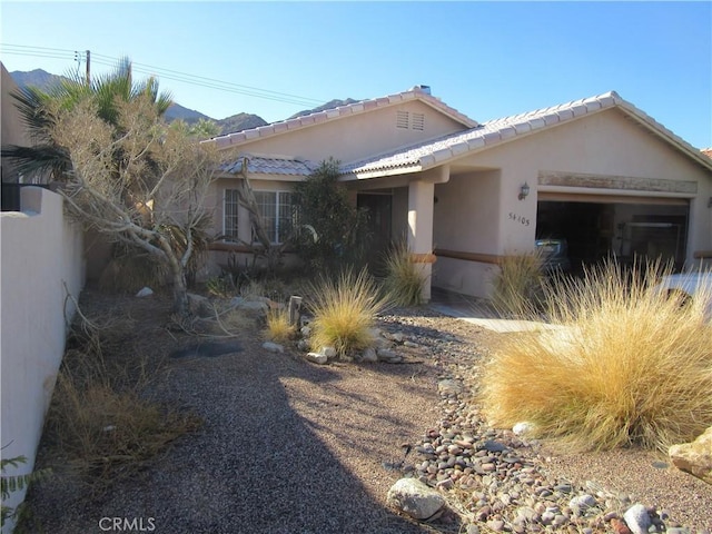 view of front of house featuring a tiled roof, a mountain view, stucco siding, and an attached garage