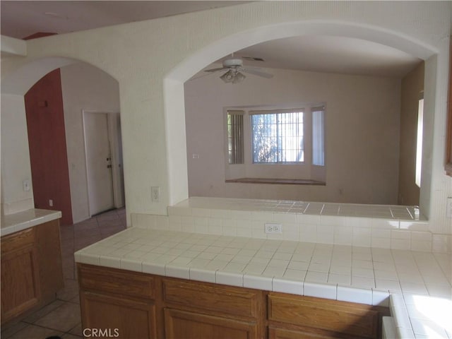 kitchen featuring brown cabinets, light countertops, a ceiling fan, and lofted ceiling