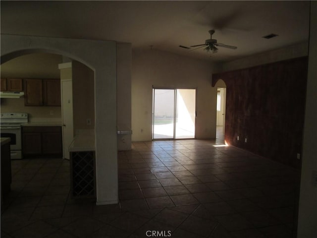 spare room featuring visible vents, lofted ceiling, arched walkways, a ceiling fan, and dark tile patterned flooring