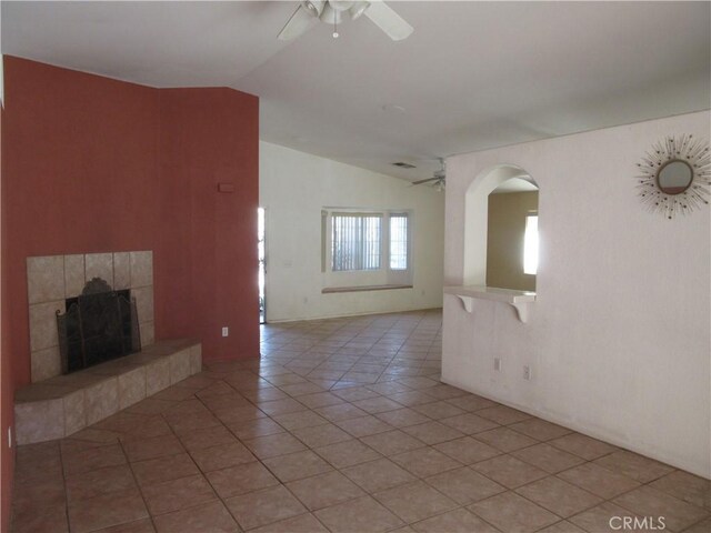 unfurnished living room with light tile patterned floors, lofted ceiling, ceiling fan, and a tile fireplace