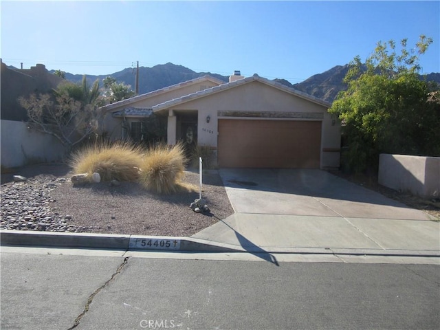 ranch-style house featuring a mountain view, a garage, driveway, and stucco siding