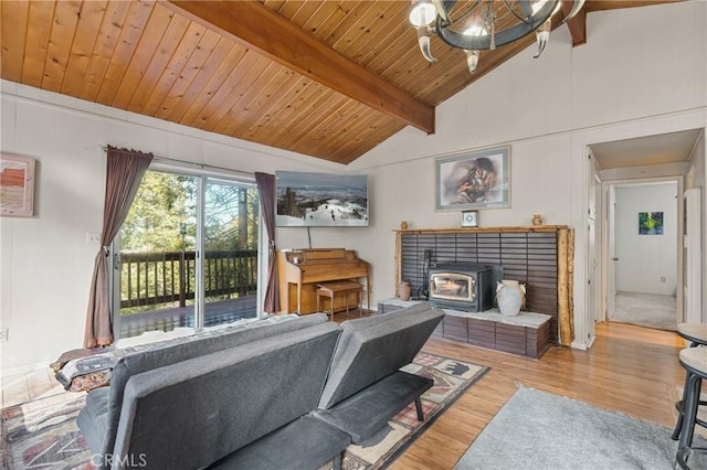 living room with vaulted ceiling with beams, wood ceiling, wood-type flooring, a chandelier, and a wood stove