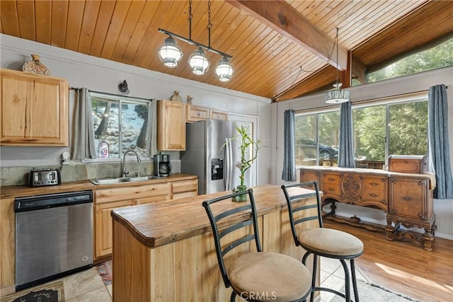 kitchen featuring sink, appliances with stainless steel finishes, lofted ceiling with beams, a kitchen island, and decorative light fixtures