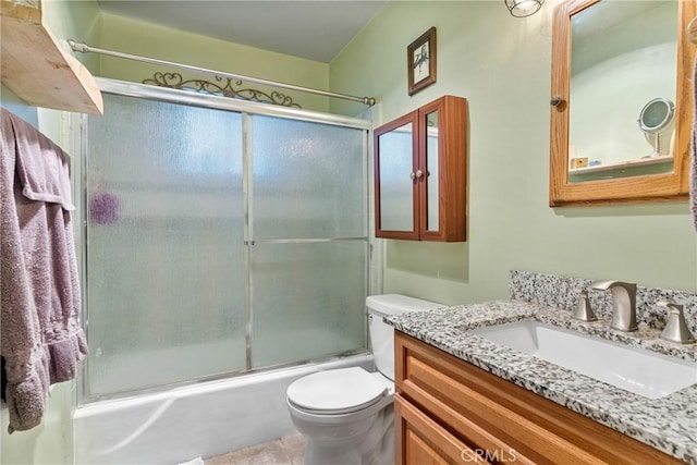 full bathroom featuring toilet, vanity, and shower / bath combination with glass door