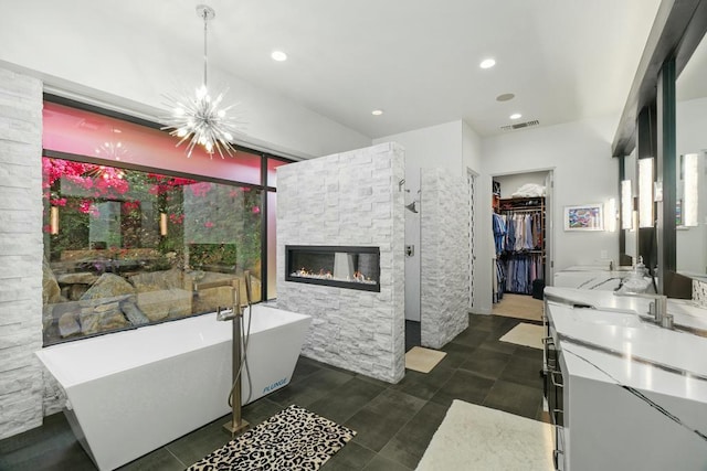 bathroom with vanity, a bathtub, a fireplace, and an inviting chandelier